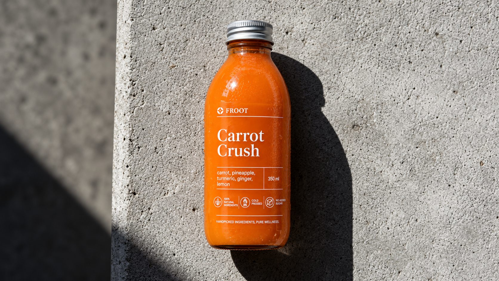 A bottle of Carrot Crush on sunlit concrete